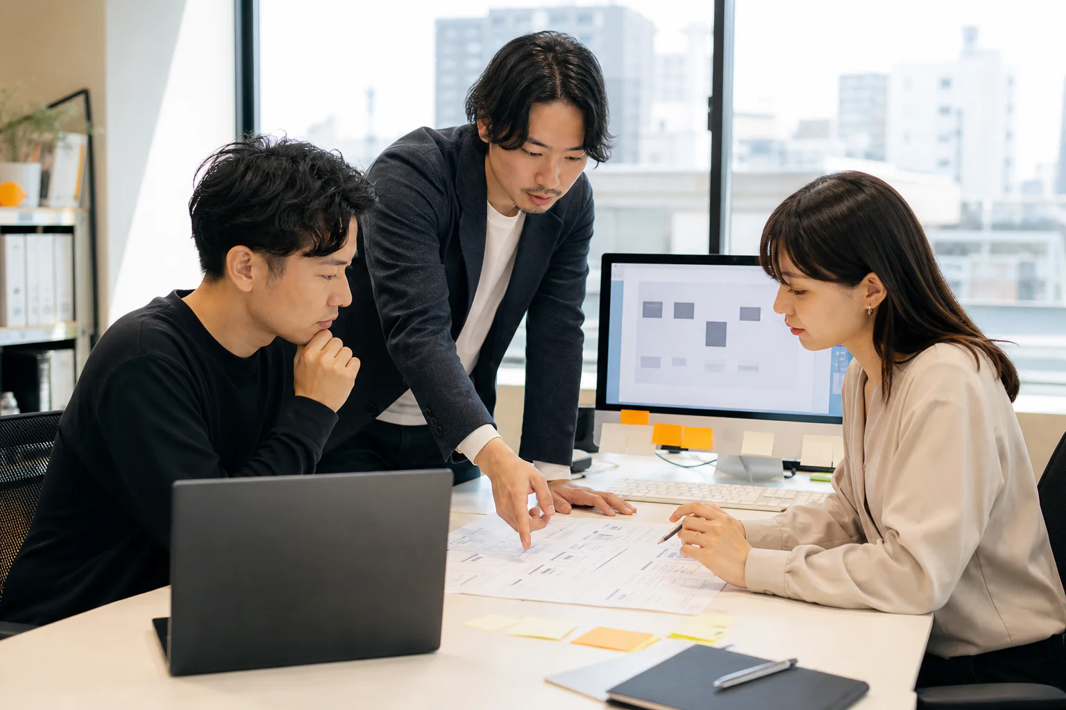 資料とノートパソコンを囲み課題を整理するチーム